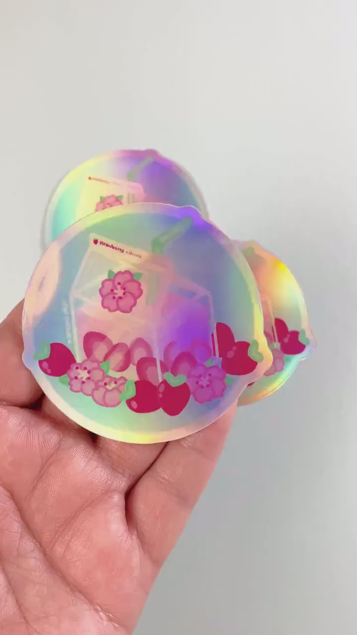 a hand holding a holographic sticker with flowers on it