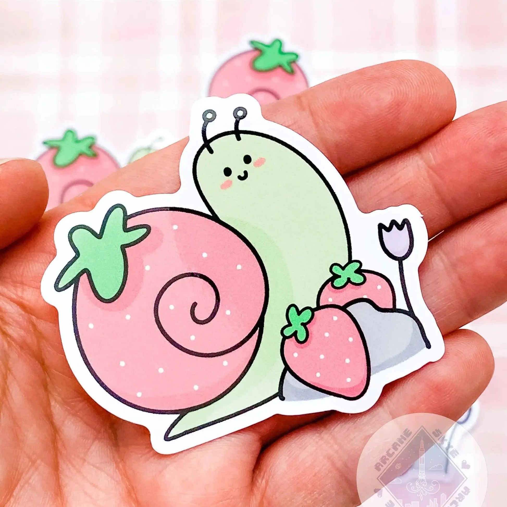 a hand holding a sticker with a snail on it