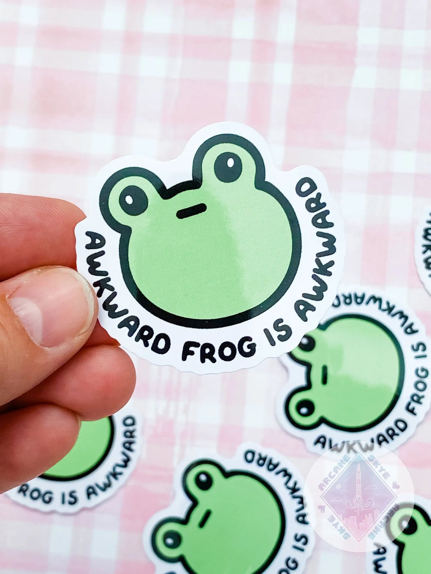 a person holding a sticker with a frog on it