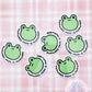 a group of frog stickers sitting on top of a pink checkered table cloth