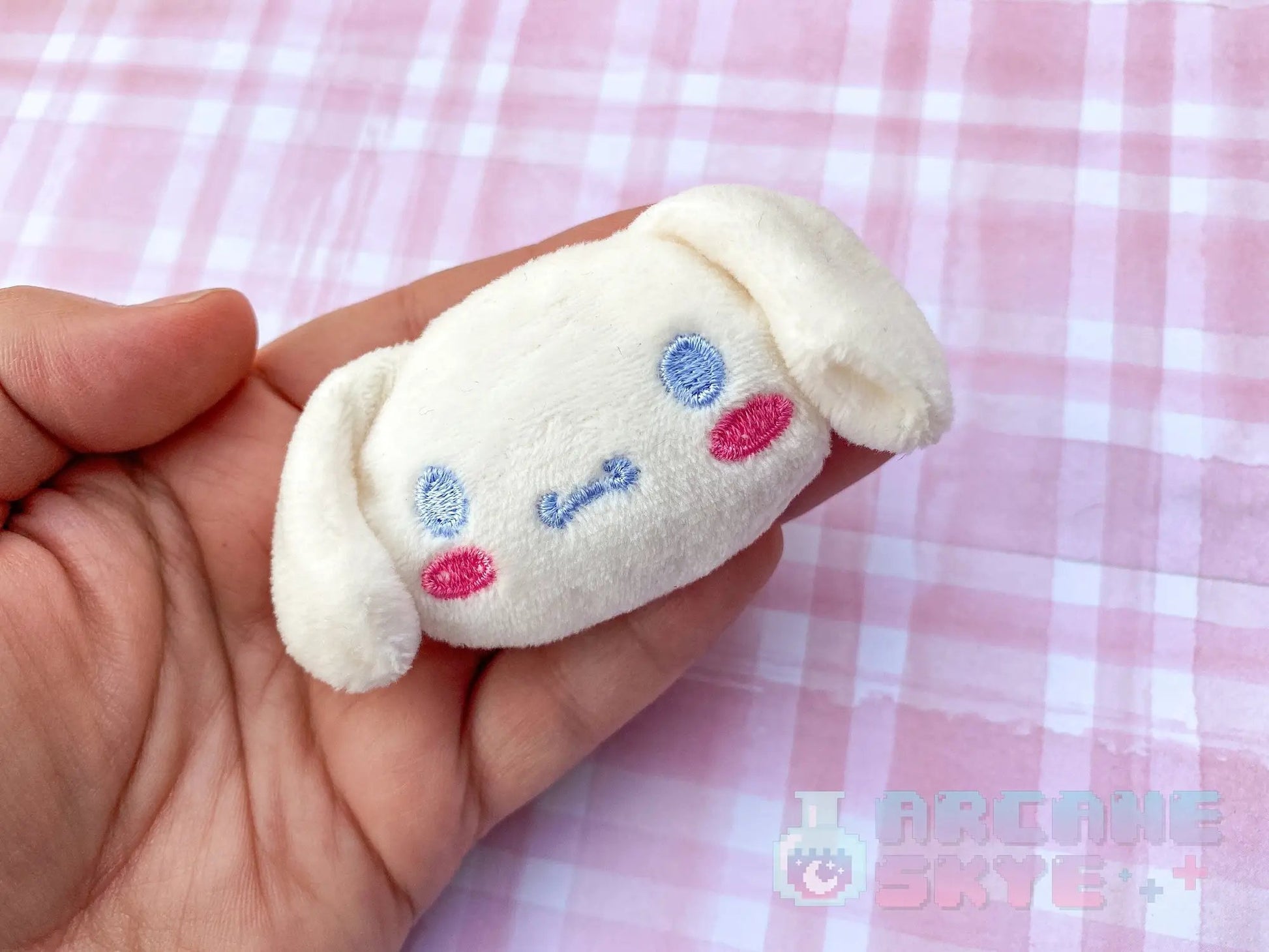 a hand holding a small white stuffed animal
