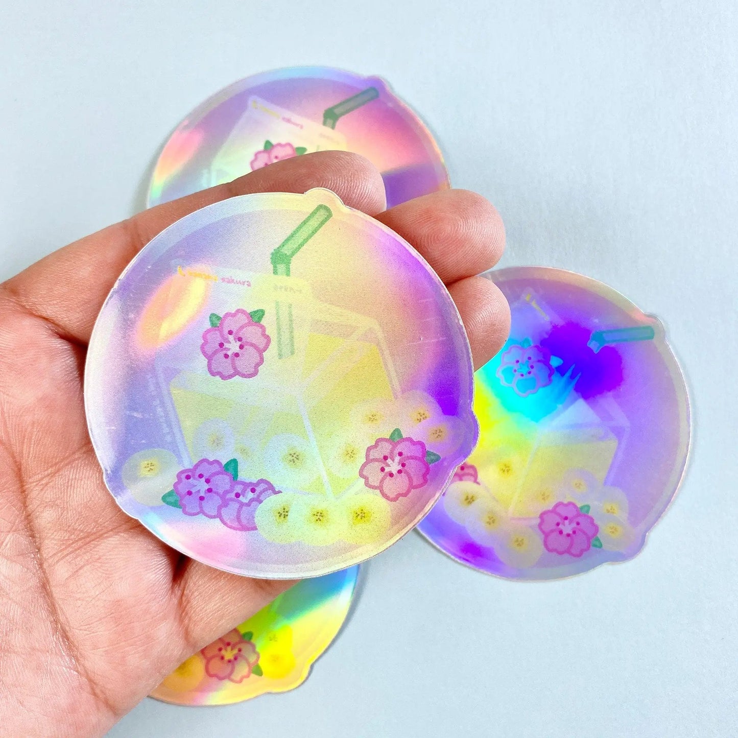 a hand holding a pair of holographic stickers
