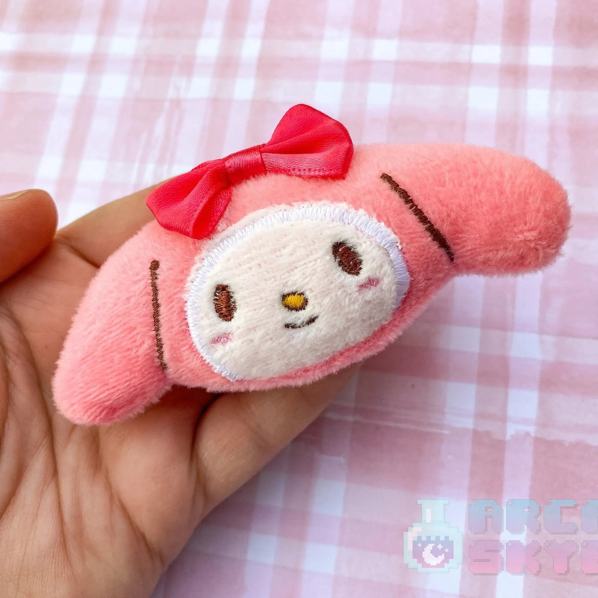 a hand holding a pink stuffed animal with a red bow