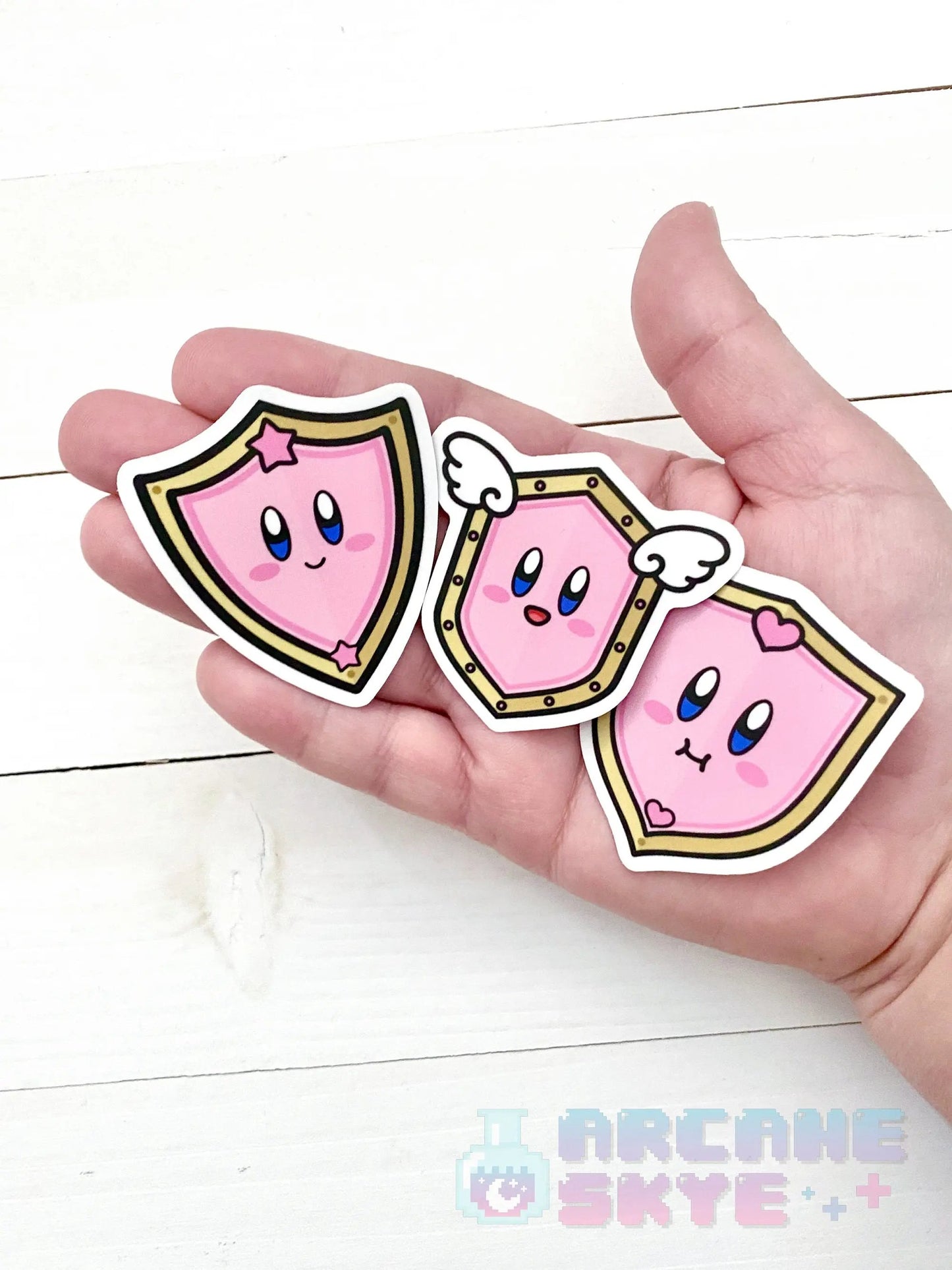 a person holding three pink stickers in their hand