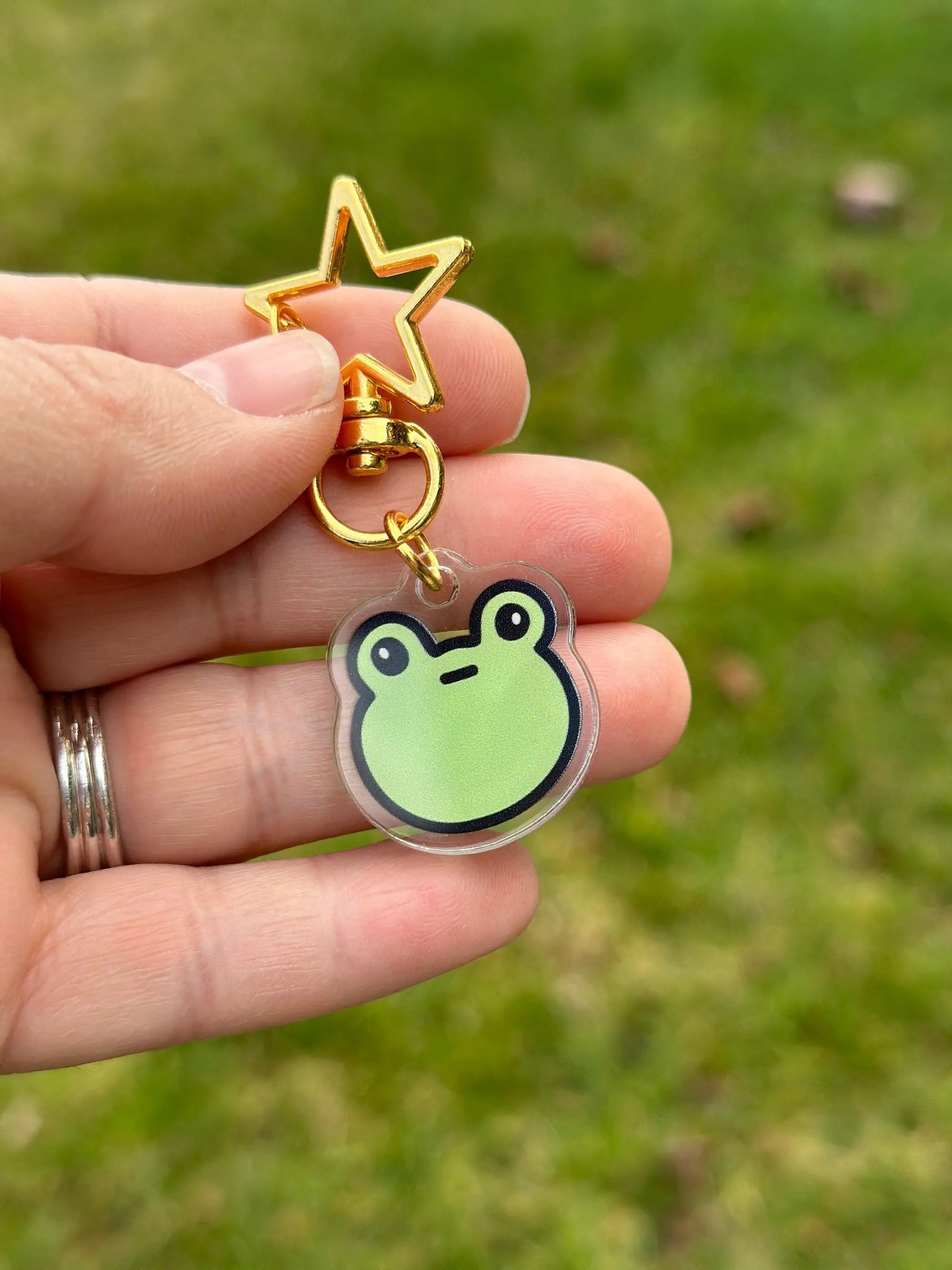 a person holding a keychain with a frog on it